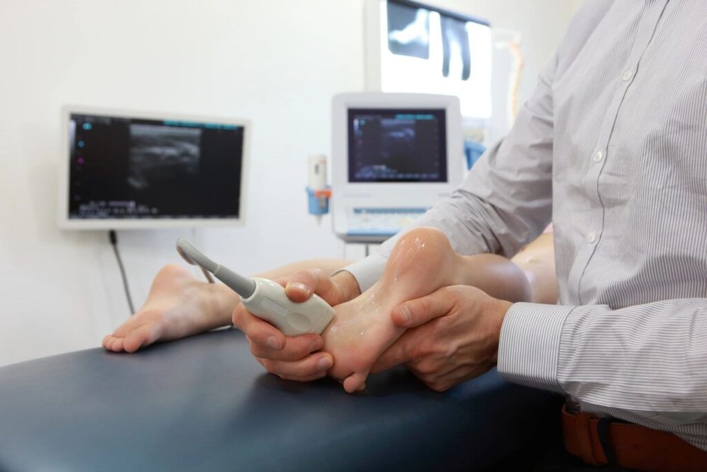 A person holding their foot while using a remote control.